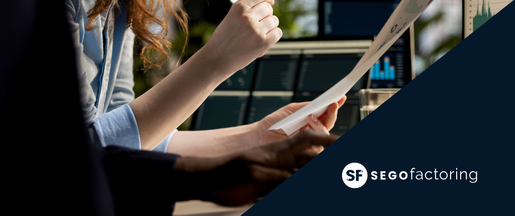 Profesionales revisando documentos financieros frente a pantallas con gráficos, representando soluciones de liquidez para pymes mediante factoring – SEGO Factoring.