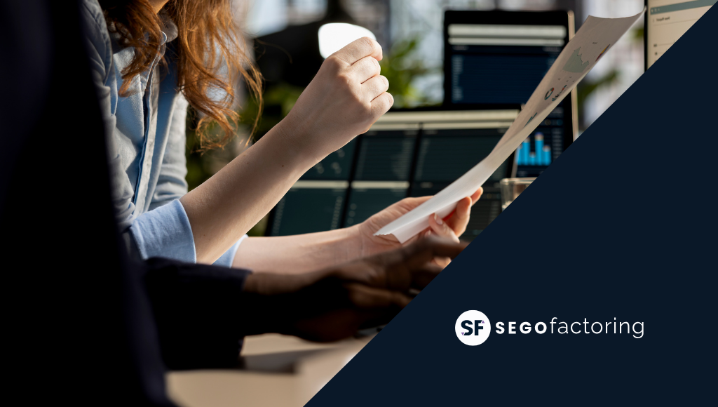 Profesionales revisando documentos financieros frente a pantallas con gráficos, representando soluciones de liquidez para pymes mediante factoring – SEGO Factoring.